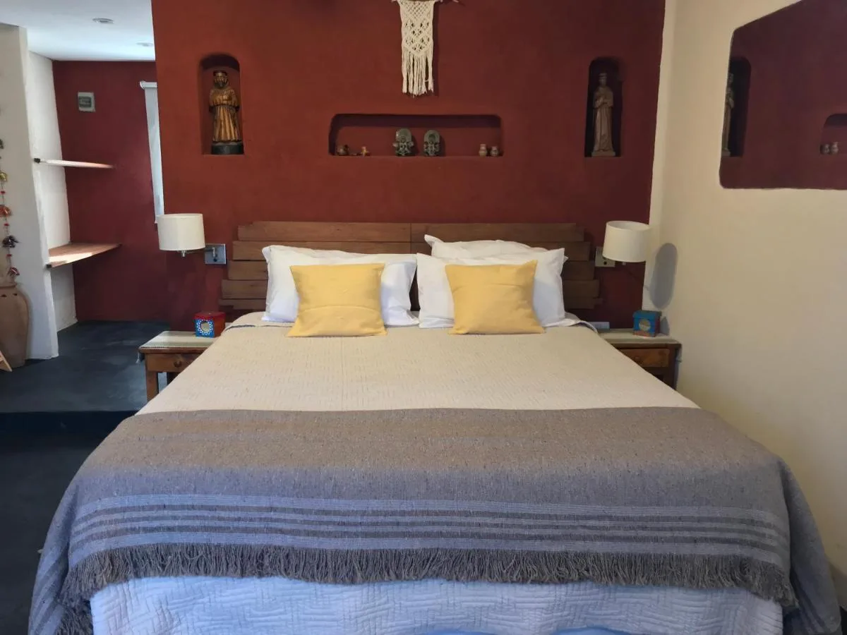 Dormitorio con cama doble y almohadones amarillos, Taos Pueblo, cabañas en Capilla del Monte