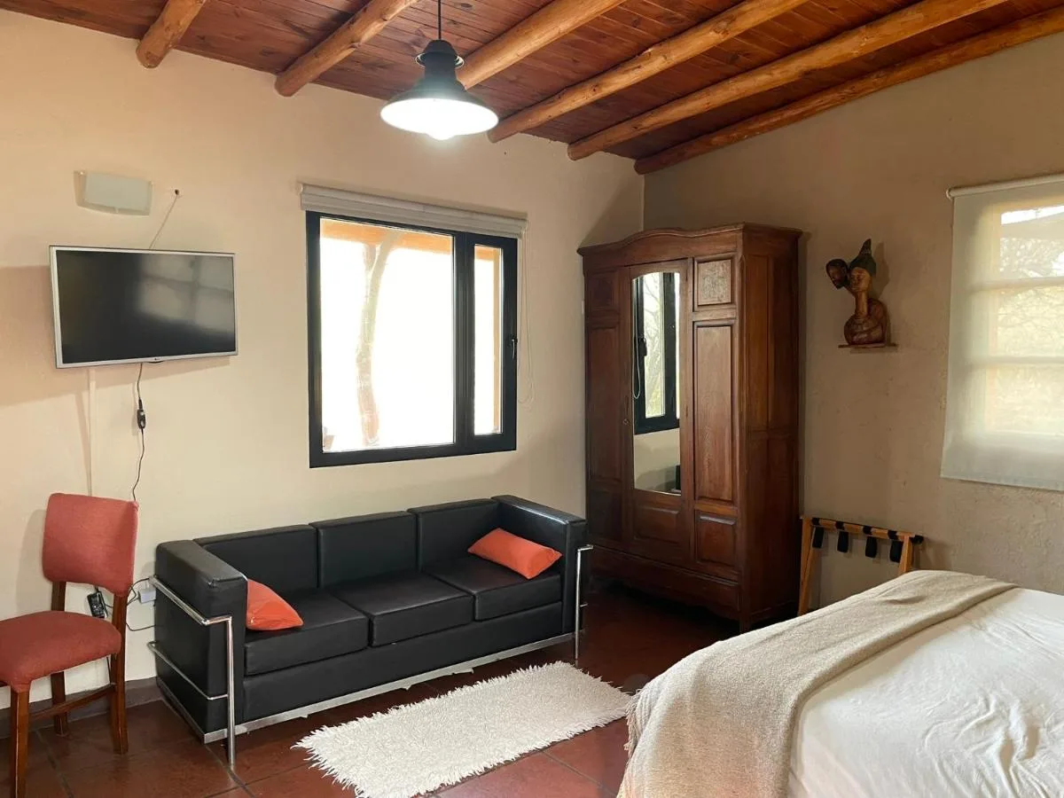 Dormitorio con sillón y TV, Taos Pueblo, cabañas en Capilla del Monte
