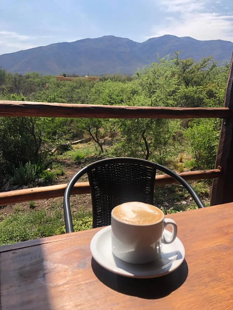 Café en la galería de madera con vista al monte y las sierras
