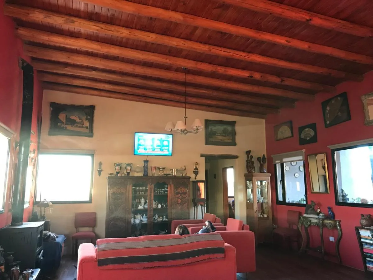 Living con techo de vigas y sillones rojos, Taos Pueblo, cabañas en Capilla del Monte