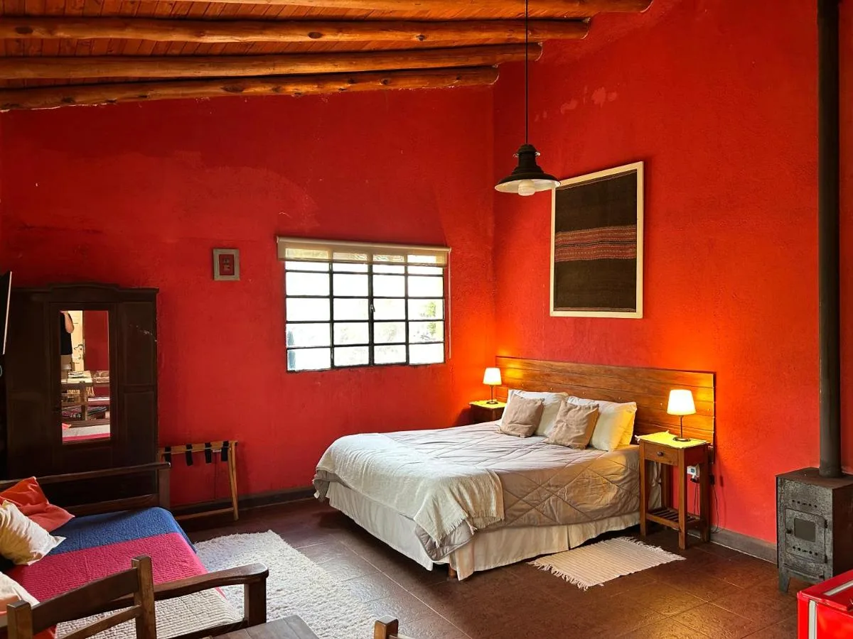 Dormitorio con paredes rojas y cama doble, Taos Pueblo, cabañas en Capilla del Monte