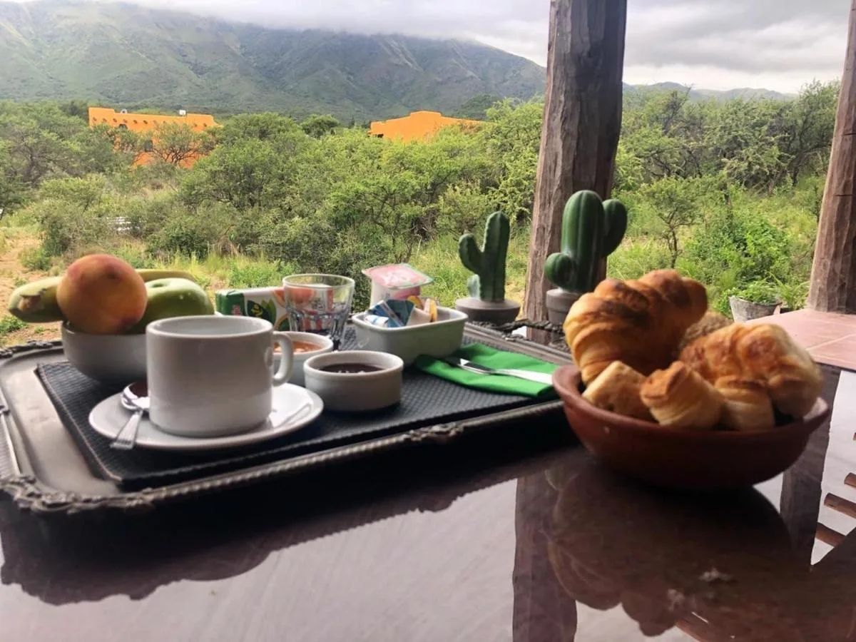 Bandeja de desayuno con café, medialunas y frutas frente a las sierras