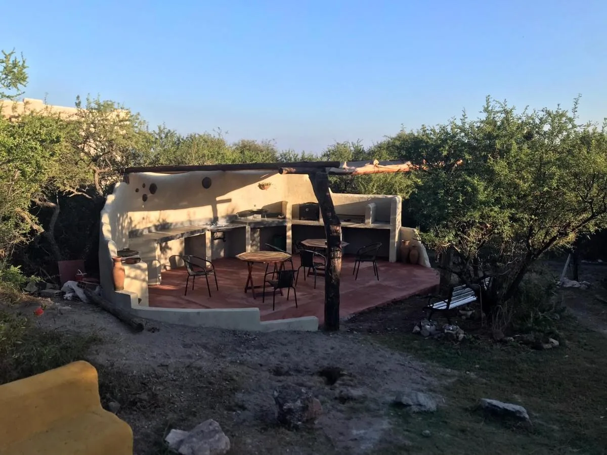 Sector de parrilla y fogón con mesas en el monte